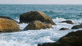 Waves crash against rocks at beach, sea spray in air, sunlight reflects on water at dusk. Natural ocean wave motion, hit rough stone coast in evening. Nature scene for calm, travel, atmosphere. Slowmo - Powered by Shutterstock - Get 15% off with code: PIKWIZARD15
