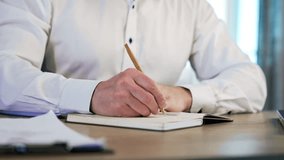 Hands of a male wearing white shirt taking notes into the paper book. Close up view of a handwriting with a ball pen. - Powered by Shutterstock - Get 15% off with code: PIKWIZARD15