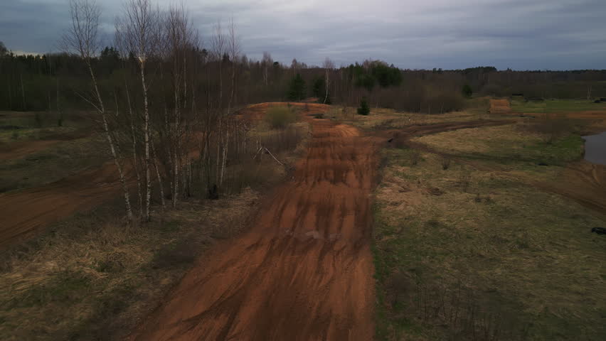Aerial view of dirt road cutting through grassland with scattered trees