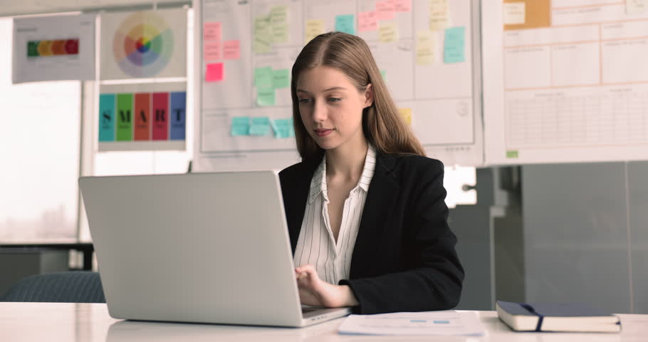 Pretty European employee working on laptop in office, engaged in busy workflow using modern wireless tech, lead formal correspondence to corporate clients by e-mailing, solve business issues remotely Royalty-Free Stock Footage #3480481389