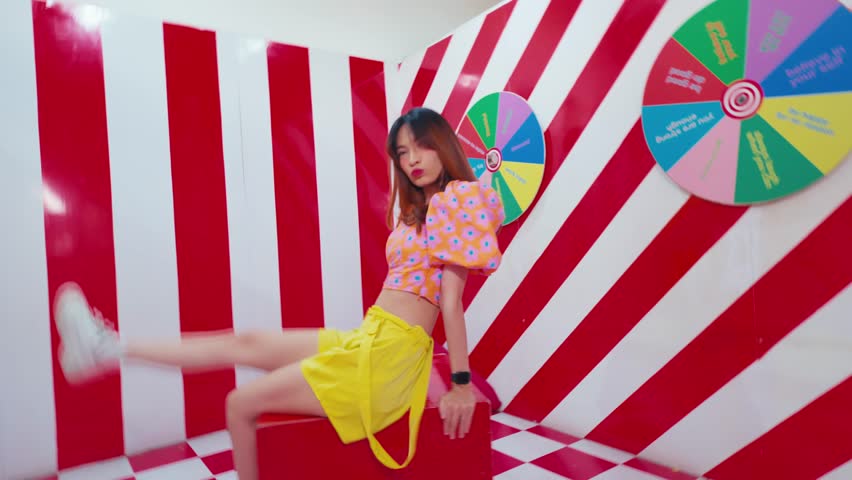 Abstract blur of a person walking in a vibrant, colorful corridor with geometric patterns and a spinning wheel during the daylight