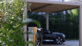 Home station for charging electrical vehicles. 4K video with an electric power station with outlet and charger for parked cars in front of the house.
