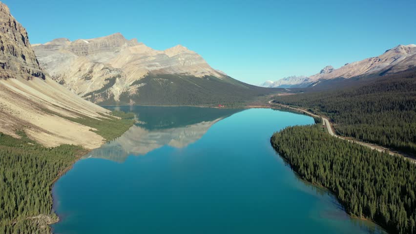 Aerial view of tranquil Bow Lake and the reflection of Mount Jimmy Simpson on a completely clear day, in the Canadian Rockies.