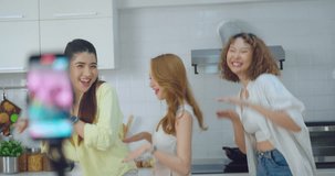 Three friends enjoy a fun moment while creating a lively cooking video in a well-lit, modern kitchen.