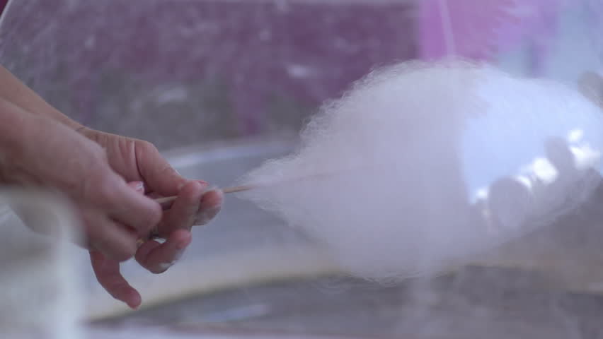 A close-up capturing the delicate process of spinning fluffy cotton candy onto a wooden stick, a whimsical treat at a fair Royalty-Free Stock Footage #3480564323