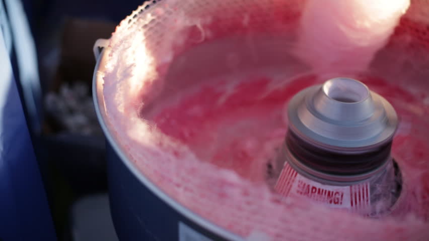 A close-up view capturing the vibrant pink swirls of cotton candy as it's spun to perfection, with machinery in action. Royalty-Free Stock Footage #3480564657