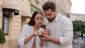 Young Caucasian woman man discussing travel tour honeymoon together sights search way couple using smartphone tourist outside city street urban gps app geo location navigator service route telephone - Powered by Shutterstock - Get 15% off with code: PIKWIZARD15