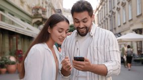 Caucasian happy couple enjoy excited man woman shocked lucky success victory mobile phone smartphone reading message good news amazed surprised open mouth city outdoors urban gen z win wonder awesome - Powered by Shutterstock - Get 15% off with code: PIKWIZARD15