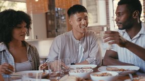 Group of multi-racial friends sitting around table enjoying meal at dinner party making cheers with water- shot in slow motion - Powered by Shutterstock - Get 15% off with code: PIKWIZARD15