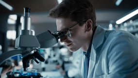 Close Up Portrait of a Young Microbiologist Wearing Glasses and Looking Through the Microscope, Analyzing Sample Cells. Cheerful Scientist Working in a Medical Science Laboratory - Powered by Shutterstock - Get 15% off with code: PIKWIZARD15