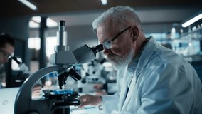 Medical Research and Development Laboratory: Senior Caucasian Male Scientist in Glasses Looking at a Sample in a Petri Dish Under a Microscope in an Advanced Biotechnology Lab - Powered by Shutterstock - Get 15% off with code: PIKWIZARD15