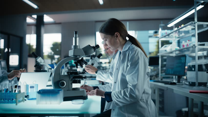 Portrait of a Beautiful Caucasian Student Working on a Research Project in College. Medical Research Scientist Looking at Biological Samples Under a Microscope in an Applied Science Laboratory