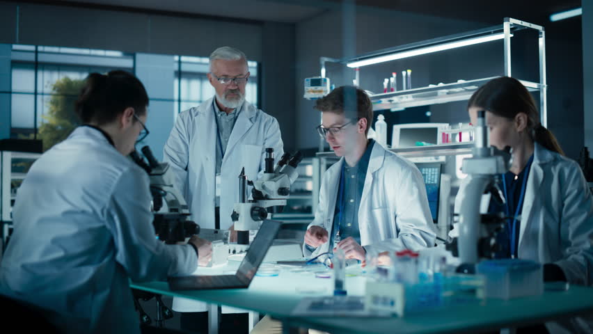 PhD Professor Teaching a Group of Science Students the Basics of Biological Engineering. Head of Laboratory Observing How Young Researchers Work with Equipment and Writes Down Their Findings - Powered by Shutterstock - Get 15% off with code: PIKWIZARD15