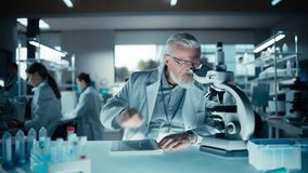 Portrait of a Middle Aged Scientist Working in a Laboratory, Using Advanced Microscope, Writing Down Research Data in a Paper Notebook. Caucasian Biotechnology Specialist Using Modern Tools - Powered by Shutterstock - Get 15% off with code: PIKWIZARD15