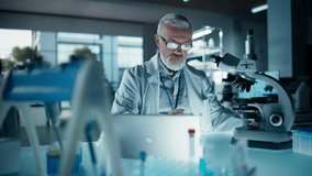 Medical Research and Development Laboratory: Middle Aged Head Scientist Working on Research Project, Looking at a Sample in a Petri Dish Under a Microscope and Writing Report on a Laptop Computer - Powered by Shutterstock - Get 15% off with code: PIKWIZARD15