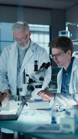Vertical Screen: Professor Teaching a Group of Science Students the Basics of Biological Engineering. Head of Laboratory Observing How Researchers Work with Equipment and Writes Down Their Findings