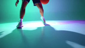 Jump by jump. Cropped image of male legs, basketball player in motion, showing skills in ball dribbling on gradient green, cyan background in neon. Concept of professional sport, competition, game