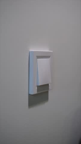 A female hand turns on and off the light by pressing the switch button in the room. Lights on and off.