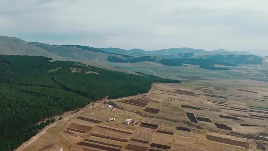 Aerial wide angle view of typical  agricultural landscape  with green fields in the foreground blue sky with clouds casting shadows on the land. 
