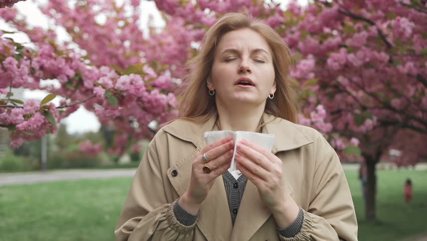 Health issues. Pretty young blonde woman having alergy symptoms from blooming sakura tree pollen in spring. Female with pollen allergies of sneezing outdoors Royalty-Free Stock Footage #3481100111