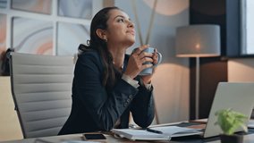 Happy businesswoman holding mug with content smile in cozy office closeup. Joyful professional taking break enjoying coffee. Serene lady feeling satisfaction dreaming future after busy workday alone - Powered by Shutterstock - Get 15% off with code: PIKWIZARD15