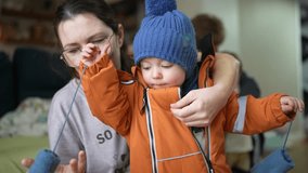 mom dresses baby in suit and overalls, going for a walk outside in winter. happy family kid dream concept. baby boy gets dressed for the street mom lifestyle helps the child get dressed - Powered by Shutterstock - Get 15% off with code: PIKWIZARD15