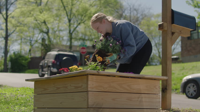 Young woman planting and watering flowers on a warm spring afternoon