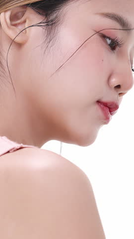 Vertical footage beautiful young Asian woman with healthy facial skin isolated over white background for skincare commercial product advertising. Slow motion shot.