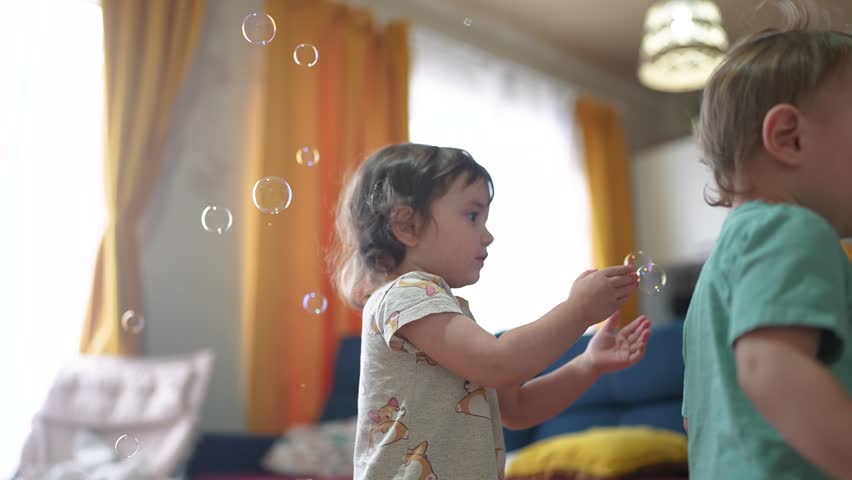 baby group playing bubbles indoors. happy family kid dream concept. baby group catching soap bubbles with their hands. group of children playing with soap fun bubbles having