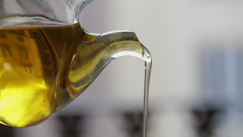 Pouring olive oil in different dishes close-up. Using in cooking for frying foods or as a salad dressing omega 3. Olive oil is popular supplement for meals and salads. 