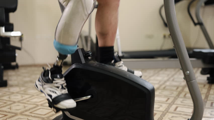 Press machine, Leg adaptation, Machine workout. Fitness enthusiast with prosthetic leg uses leg press machine at gym, with other devices around. Royalty-Free Stock Footage #3481284955