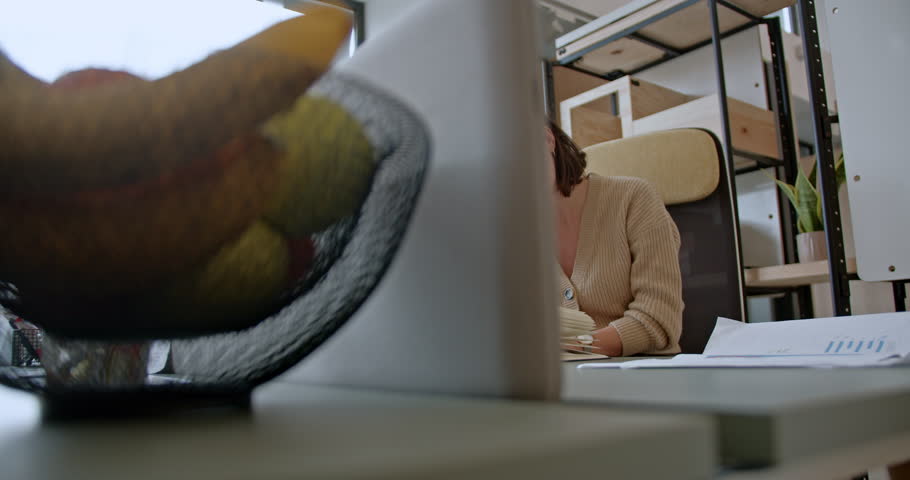 In a home office setting, a diligent young woman in glasses is engrossed in reading a book, with papers and a laptop nearby, showcasing her focus and dedication to her work or studies. Royalty-Free Stock Footage #3481353011