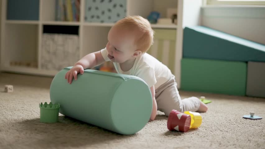 one year old boy plays in the child's room with a roller, montessori tower