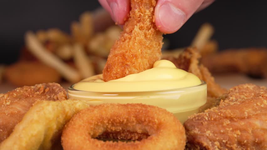 Hand dips crunchy fried shrimp or prawn into cheese sauce in macro. Footage for advertise fast food, takeaway junk food, roadside cafe, supermarket display, food truck, street food