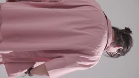 back view of casual fashion man in pink shirt wearing sunglasses moving to side view, rubbing palms and adjusting hair on grey background - Powered by Shutterstock - Get 15% off with code: PIKWIZARD15