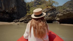 Woman sitting on boat passing lagoon. Back view female travel, riding on gondola, sitting on ship bow and looking enjoy beautiful nature in a wicker hat in summer day. Tourism joy, sunny day concept.