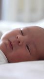 Infant sleeping in its bed. Baby opens eyes during its dream and smiling a little. Emotions on a pretty baby face. Vertical video