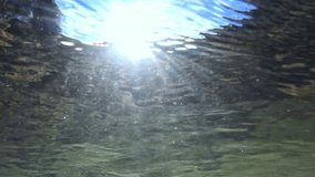 Underwater video of a stream with stones and sunbeams in flowing water