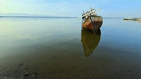 A brief video clip depicting a damaged vessel situated in a cove, accompanied by the soothing ambiance of gentle waves.