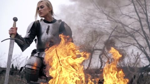 Wounded Jeanne d'Arc is kneeling by the fire