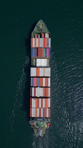 A container ship moves steadily through the ocean, carrying stacked containers