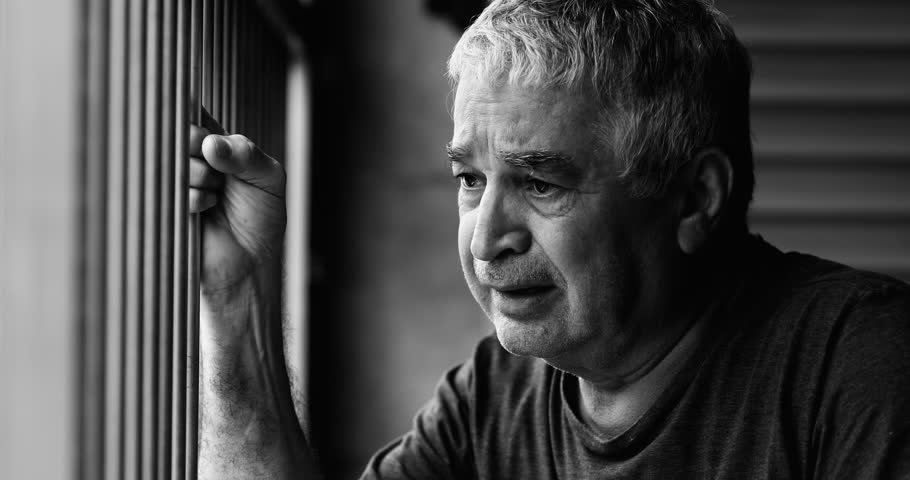 Aging Senior Man in Despair, Confined at Home, Grips a Metal Bar and Cries, Overcome by Loneliness and Mental Illness, a Poignant Portrait of Struggle and Isolation in intense black and white