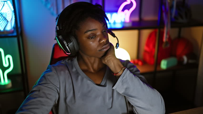 Serious young black woman with dreadlocks in gaming room, hand on chin, deep in thought, playing intense game, face full of concentration and confusion Royalty-Free Stock Footage #3481912043