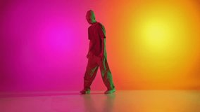 Cool attitude young man, talented freestyle dancer dancing in motion in neon light against gradient pink-yellow background. Concept of hobby, sport, creativity, fashion and style, motion, action. Ad