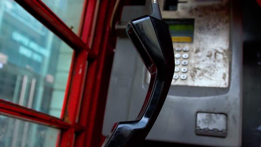 Red british telephone box interior, phone handset close up. phone handset telephone hanging upside down 