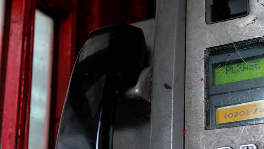 Red british telephone box interior, phone handset close up. picking up answering call and putting down hanging up call