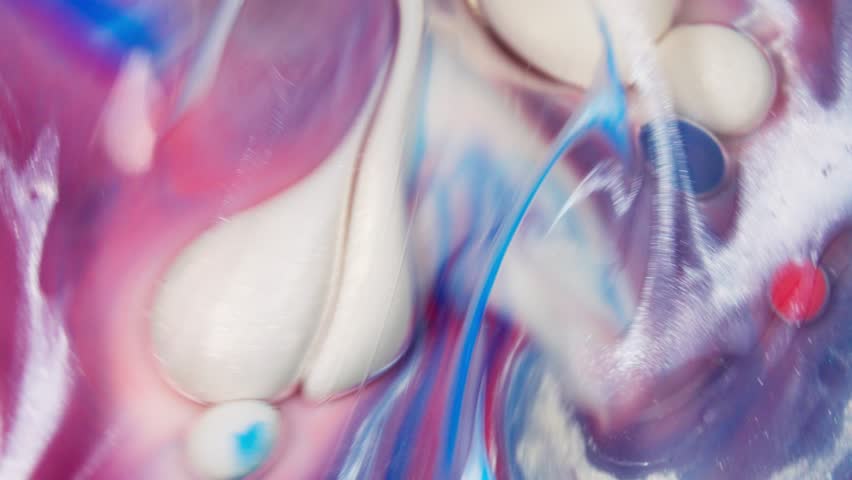Liquid ink swirling and flowing with blue red purple and white colors.