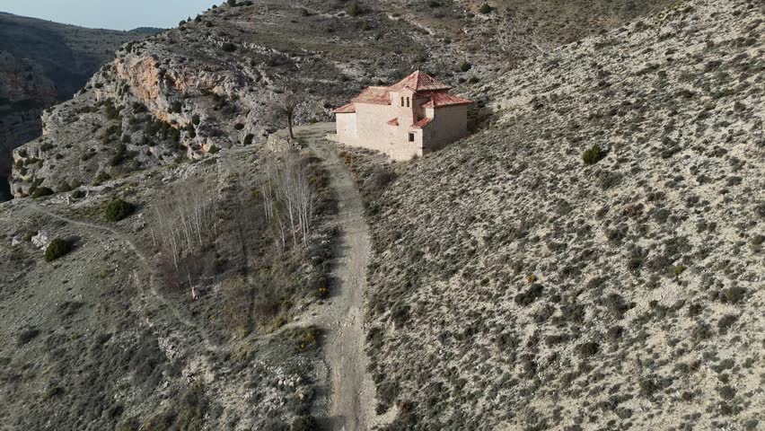 Aerial drone shot flying backward of an isolated Hermitage in an arid Landcape. Nuertra Señora del Carmen. Albarracin, Teruel, Spain. 4K