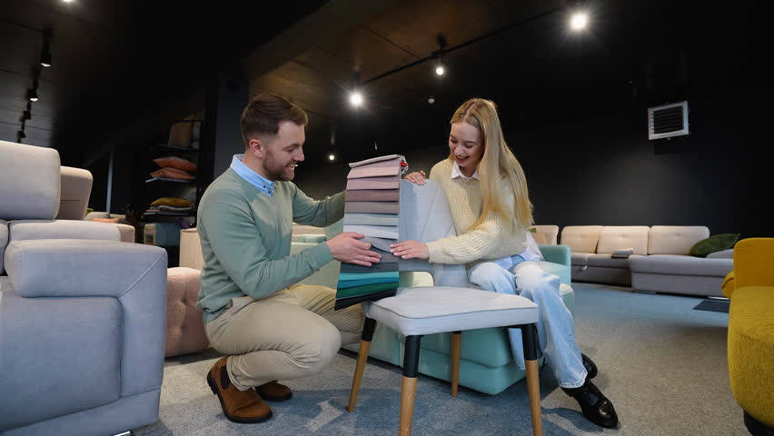 A man and woman choosing upholstery fabric color and texture from various colorful samples for armchair in a store Royalty-Free Stock Footage #3482052259