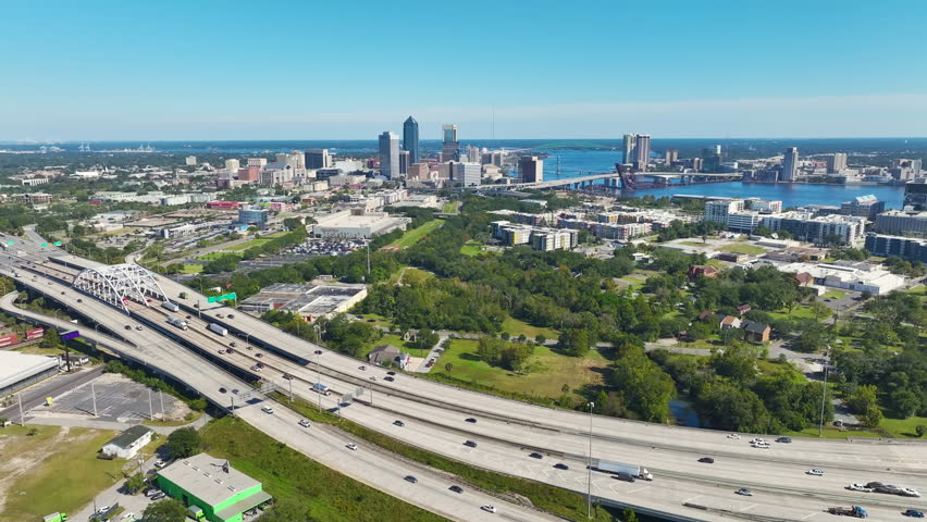 Jacksonville city with high office buildings and American freeway intersection with fast moving cars and trucks. USA transportation infrastructure concept